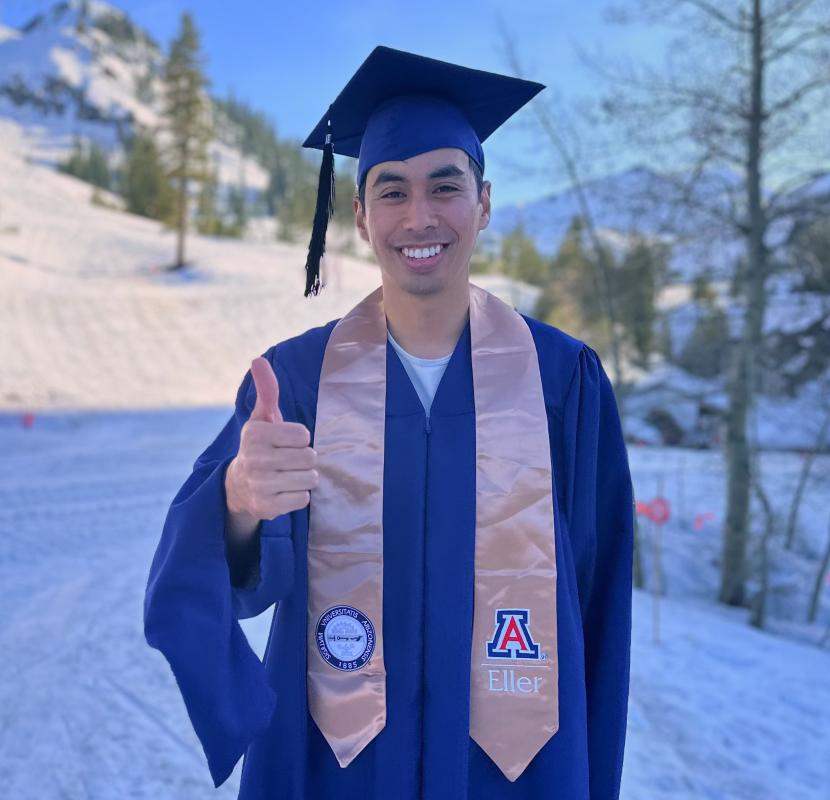 image of ethan in his graduating cap and gown, smiling and giving a thumbs up.